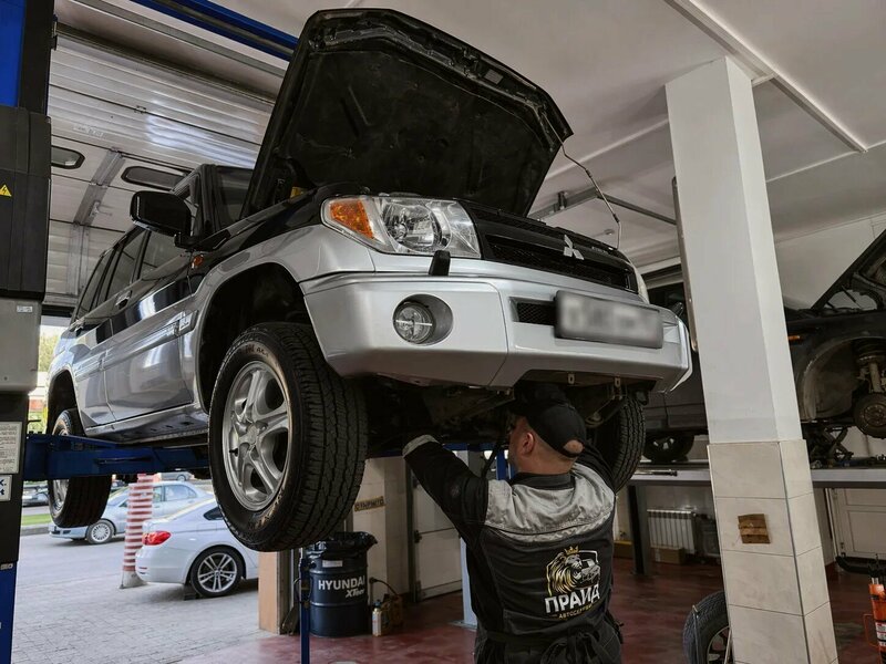 Механик автосервиса «Прайд» обслуживает Mitsubishi на подъёмнике